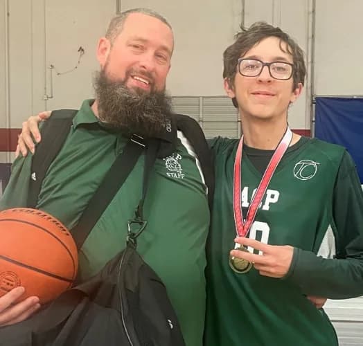 ACP basketball coach with a student holding his medal