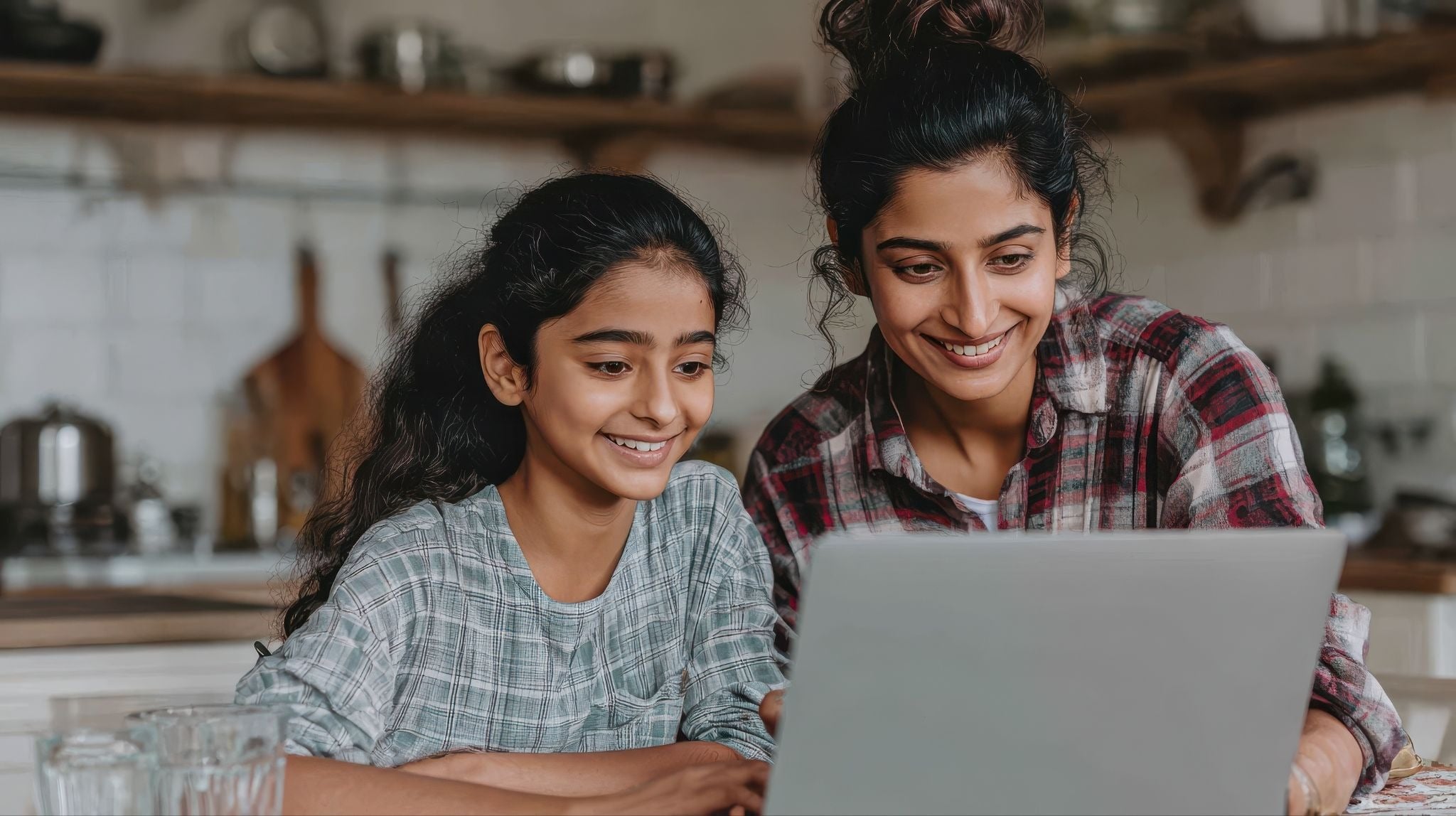 Two smiling people looking at a laptop screen.
